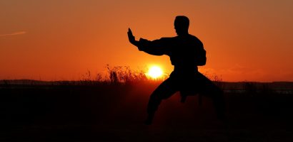 Photo of person in a karate stance in front of the sun